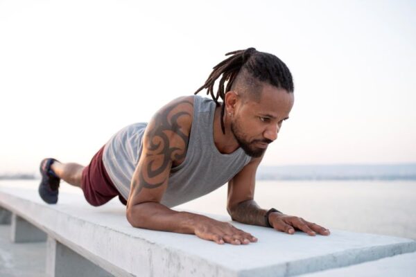 African American man wearing workout clothes and holding a plank pose