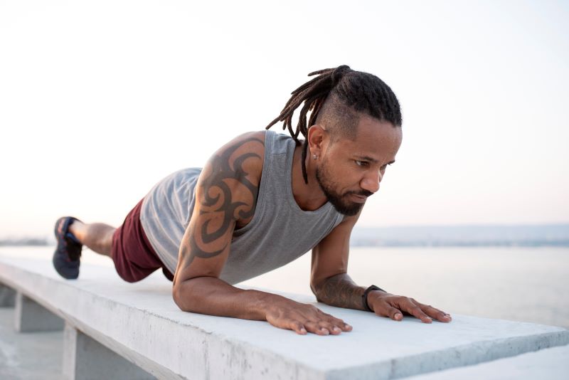 African American man wearing workout clothes and holding a plank pose