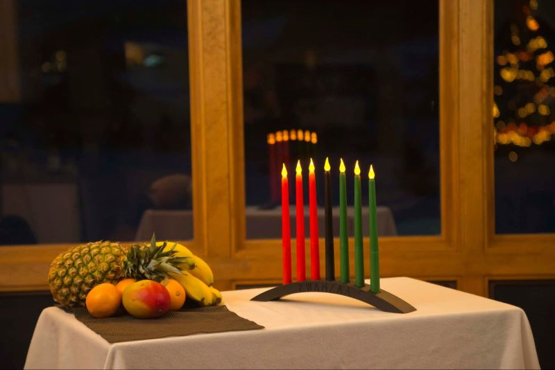 table set up for Kwanzaa, with a lit kinara and fruits in a household