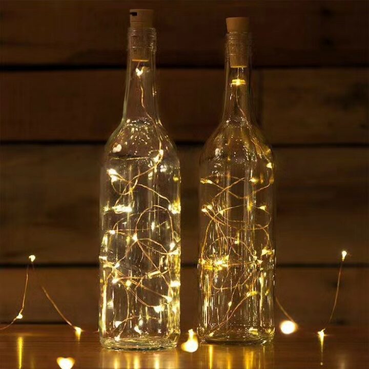 string lights lit up inside wine bottles in a darkened room