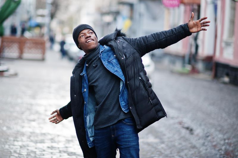 Black man bundled up in a beanie and jacket, enjoying the cold weather 