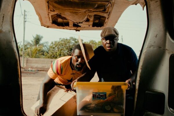 Still from movie, Letter to Goddo, with two African men looking into the back of a car