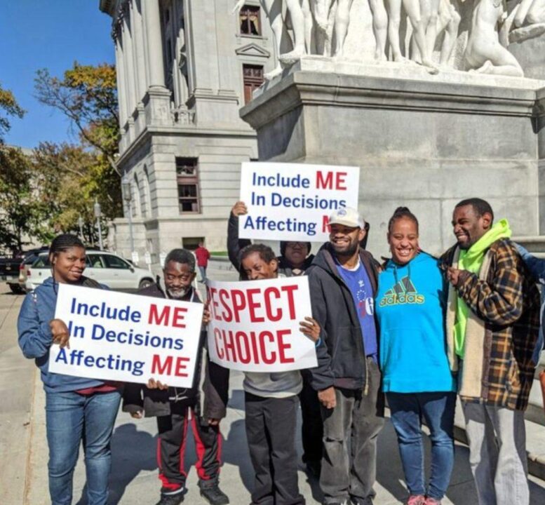 a group of African American people with disabilities holding posters saying "respect choice" and "include me in decisions affecting me"