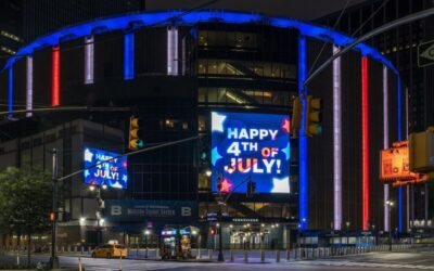 a nighttime celebration of Fourth of July, with neon signs, outside of a theater or stadium