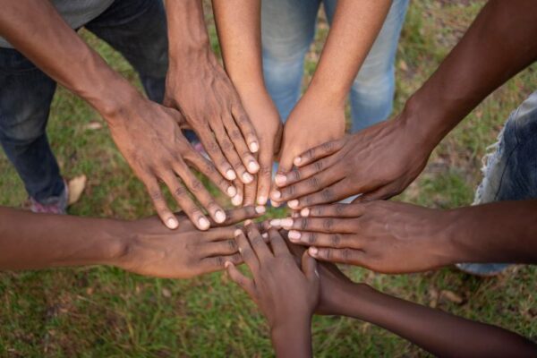 a group of people in a circle, with focus on hands piled on top of each other in the middle