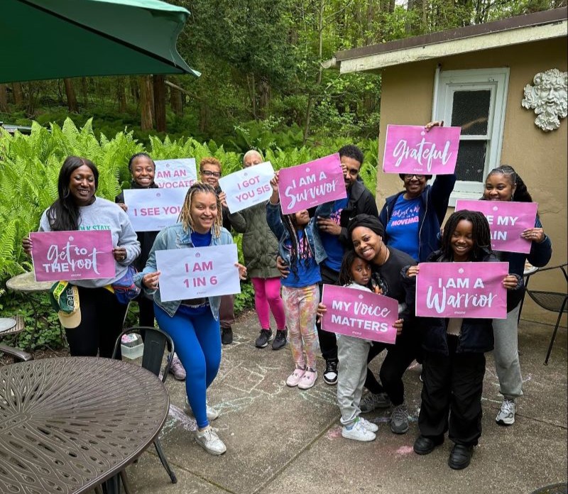 Murray and group of advocates holding up empowering signs