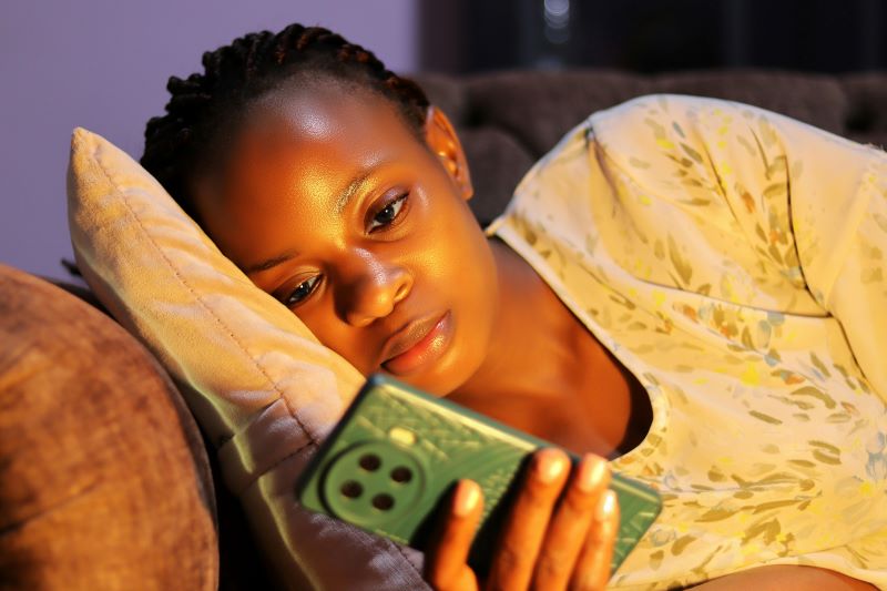 Black woman at home staring at her smartphone on the couch