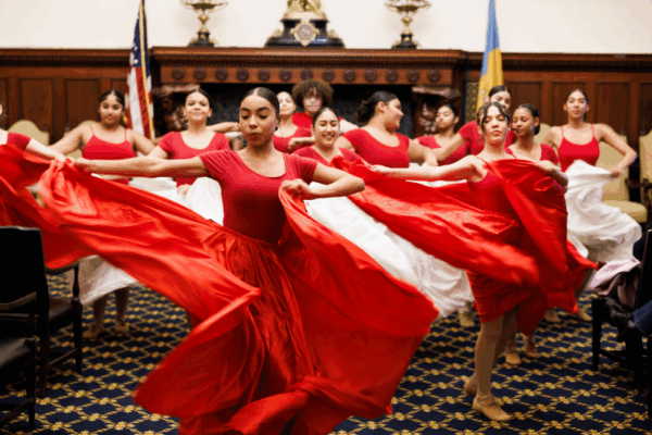 Latin cultural dancers holding large flowy skirts, performing in City Hall