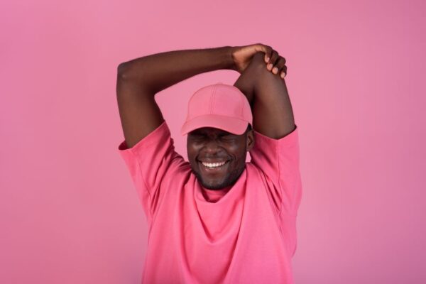 African American man in a pink baseball cap and pink shirt in front of a pink background to raise breast cancer awareness