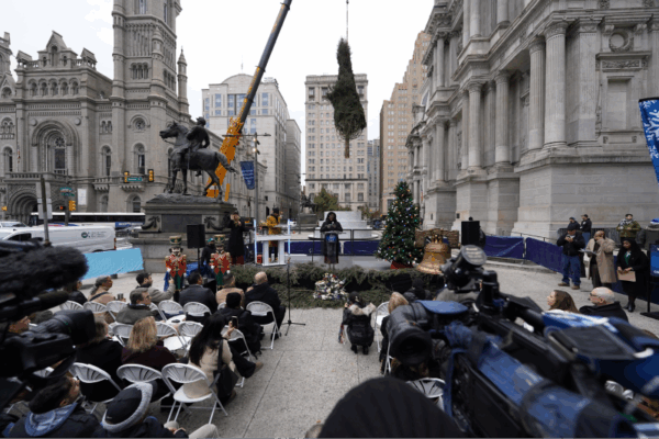 a crane placing the Christmas tree in front of City Hall Philadelphia as the mayor makes a speech