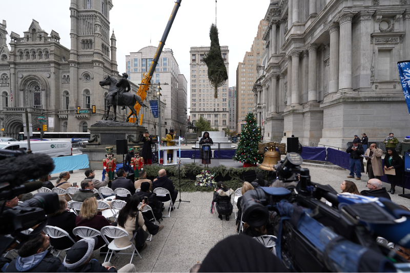 a crane placing the Christmas tree in front of City Hall Philadelphia as the mayor makes a speech