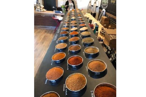rows of various spices in containers lined up on a long countertop