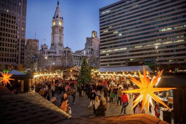 Christmas village with a view of the Christmas market shops, illumination stars, Christmas tree, and Philadelphia City Hall in the background