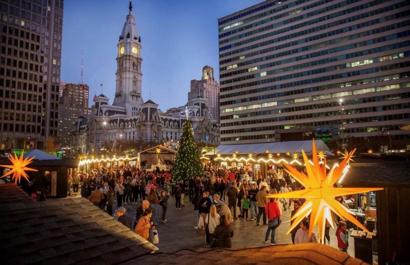 Christmas village with a view of the Christmas market shops, illumination stars, Christmas tree, and Philadelphia City Hall in the background