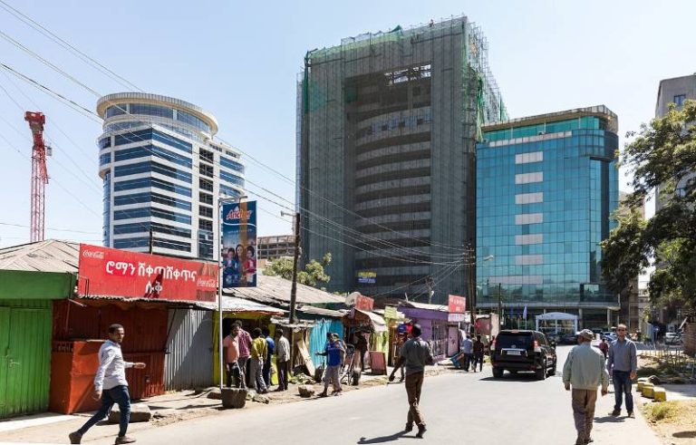 a city view of Addis Ababa, Ethiopia, with taller buildings in the background and smaller roofed shops in the foreground