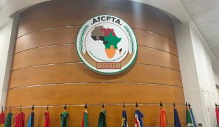 emblem of AfCFTA on a wall, with flags of different African countries lined below