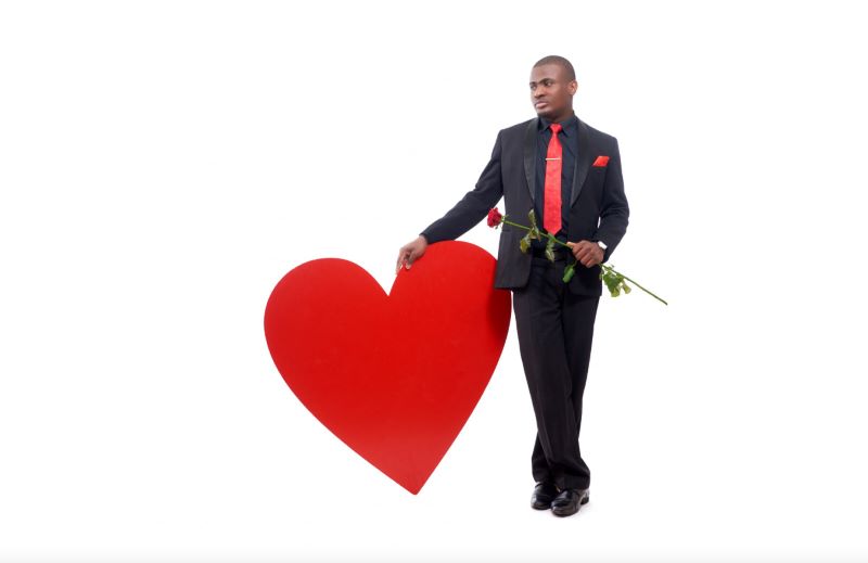 a man dressed in a suit and tie holding a rose, next to a heart