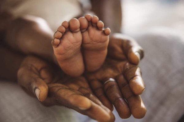 hands of a mother holding the feet of her baby