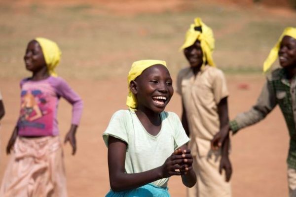 Burundi children wearing yellow headscarves, smiling outdoors