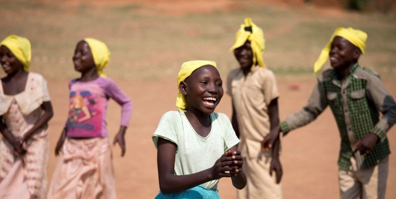 Burundi children wearing yellow headscarves, smiling outdoors