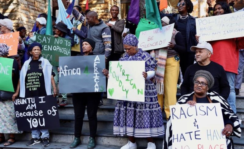group of protestors, some in traditional attire, with slogans for Africans and anti-xenophobia