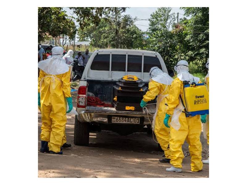 health professionals in protective suits carrying a coffin onto the back of a truck for transport
